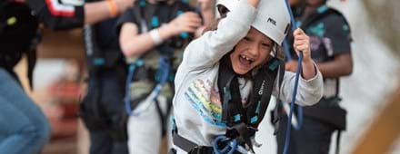 meisje heeft plezier en lacht tijdens klimmen bij outdoor klimpark Adventure City Rotterdam