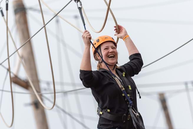 vrouw lacht tijdens klimmen bij klimpark Adventure City Rotterdam